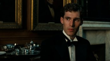 Movie still from “Chariots of Fire” (1981), directed by Hugh Hudson – A man in a tuxedo sitting in front of a painting; Close Up shot, Low angle