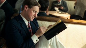 Movie still from “Chariots of Fire” (1981), directed by Hugh Hudson – A man in a suit and tie writing on a piece of paper; Medium shot, Low angle