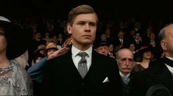Movie still from “Chariots of Fire” (1981), directed by Hugh Hudson – A man in a suit is saluting in front of a group of people; Close Up shot, Low angle