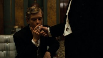 Movie still from “Chariots of Fire” (1981), directed by Hugh Hudson – A man smoking a cigarette in a suit and tie; Medium shot, High angle