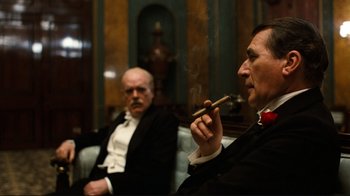 Movie still from “Chariots of Fire” (1981), directed by Hugh Hudson – Two men in suits sitting next to each other smoking; Medium shot, Low angle