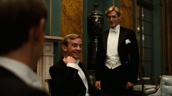 Movie still from “Chariots of Fire” (1981), directed by Hugh Hudson – Two men in tuxedos posing for a picture; Medium shot, Over the shoulder angle