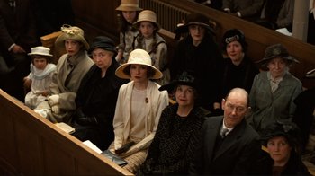 Movie still from “Chariots of Fire” (1981), directed by Hugh Hudson – A group of people sitting in a row of pews wearing hats; Wide shot, High angle