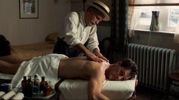 Movie still from “Chariots of Fire” (1981), directed by Hugh Hudson – A man is getting a back massage from a masseuse; Medium shot, High angle