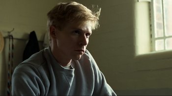 Movie still from “Chariots of Fire” (1981), directed by Hugh Hudson – A man with blonde hair sitting in front of a wall; Close Up shot, Low angle