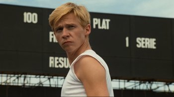 Movie still from “Chariots of Fire” (1981), directed by Hugh Hudson – A man with blonde hair standing in front of a building; Close Up shot, Low angle