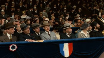 Movie still from “Chariots of Fire” (1981), directed by Hugh Hudson – A group of men in suits and hats sitting in front of an audience; Medium shot, High angle