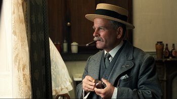 Movie still from “Chariots of Fire” (1981), directed by Hugh Hudson – An older man smoking a pipe while holding a doughnut; Medium shot, Low angle