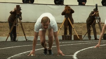 Movie still from “Chariots of Fire” (1981), directed by Hugh Hudson – A man in a white shirt is on a track; Medium shot, High angle