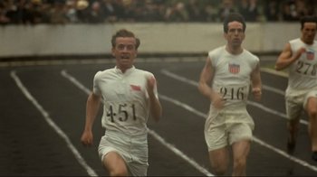 Movie still from “Chariots of Fire” (1981), directed by Hugh Hudson – Two men running on a race track in white outfits; Medium shot, High angle