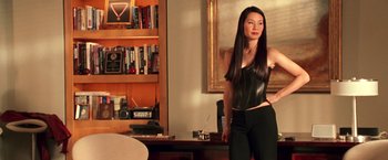 Movie still from “Charlie's Angels” (2000), directed by McG – A woman standing in front of a table in a room; Medium shot, Over the shoulder angle