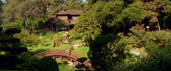 Movie still from “Charlie's Angels” (2000), directed by McG – A couple of people standing on top of a bridge in a yard; Extreme Wide shot, High angle