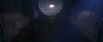 Movie still from “Charlie's Angels” (2000), directed by McG – A person standing in a dark room with a light on; Wide shot, High angle