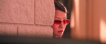Movie still from “Charlie's Angels” (2000), directed by McG – A woman wearing red sunglasses leaning against a brick wall; Close Up shot, High angle