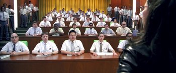 Movie still from “Charlie's Angels” (2000), directed by McG – A group of people sitting at a table in front of a curtain; Wide shot, High angle