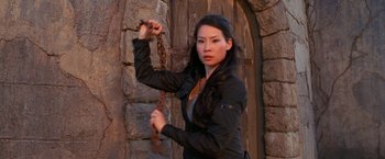 Movie still from “Charlie's Angels” (2000), directed by McG – A beautiful woman holding a chain in front of a stone wall; Close Up shot, Over the shoulder angle