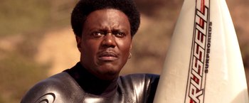 Movie still from “Charlie's Angels: Full Throttle” (2003), directed by McG – A person holding a surf board; Close Up shot, Low angle