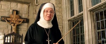 Movie still from “Charlie's Angels: Full Throttle” (2003), directed by McG – An older woman wearing a nun's outfit holding a stick; Close Up shot, Low angle