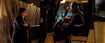 Movie still from “Charlie's Angels: Full Throttle” (2003), directed by McG – A man driving a fork lift truck in a warehouse; Medium shot, Low angle