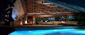 Movie still from “Charlie's Angels: Full Throttle” (2003), directed by McG – Two people sitting on a couch in a room with a pool in front of them; Extreme Wide shot, High angle