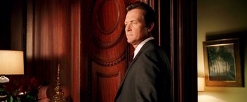 Movie still from “Charlie's Angels: Full Throttle” (2003), directed by McG – A man in a suit standing in front of a wooden door; Medium shot, Over the shoulder angle