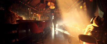 Movie still from “Charlie's Angels: Full Throttle” (2003), directed by McG – A person walking in a room with chairs and tables in the background; Wide shot, Low angle