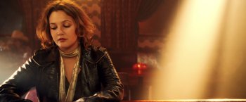 Movie still from “Charlie's Angels: Full Throttle” (2003), directed by McG – A woman sitting at a table in front of a fireplace; Medium shot, Over the shoulder angle