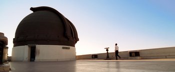 Movie still from “Charlie's Angels: Full Throttle” (2003), directed by McG – A man walking on the roof of a building near a telescope; Extreme Wide shot, Low angle