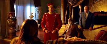 Movie still from “Charlie's Angels: Full Throttle” (2003), directed by McG – A man in a red suit standing in front of a group of people; Medium shot, Over the shoulder angle