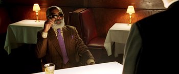 Movie still from “Charlie's Angels: Full Throttle” (2003), directed by McG – An older man sitting at a table in front of a white table cloth; Medium shot, Over the shoulder angle