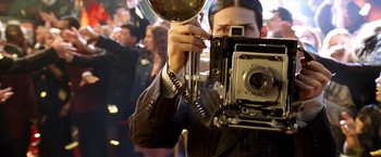 Movie still from “Charlie's Angels: Full Throttle” (2003), directed by McG – A man in a suit taking a picture with a camera; Close Up shot, Low angle