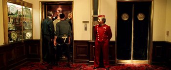 Movie still from “Charlie's Angels: Full Throttle” (2003), directed by McG – A man in a red uniform standing in front of a door; Wide shot, Low angle