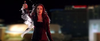 Movie still from “Charlie's Angels: Full Throttle” (2003), directed by McG – A beautiful woman in a black dress standing in front of a building at night; Medium shot, Over the shoulder angle