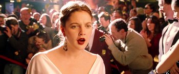 Movie still from “Charlie's Angels: Full Throttle” (2003), directed by McG – A woman with a surprised look standing in front of a group of people; Close Up shot, Over the shoulder angle