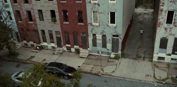 Movie still from “Charm City Kings” (2020), directed by Angel Manuel Soto – A car parked on the side of the road next to a row of buildings; Extreme Wide shot, High angle