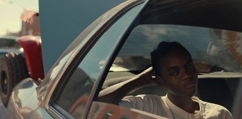 Movie still from “Charm City Kings” (2020), directed by Angel Manuel Soto – A man sitting in the driver's seat of a car while talking on a phone; Close Up shot, Over the shoulder angle