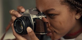 Movie still from “Charm City Kings” (2020), directed by Angel Manuel Soto – A person taking a picture with a camera; Extreme Close Up shot, Overhead angle