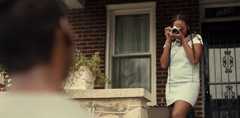 Movie still from “Charm City Kings” (2020), directed by Angel Manuel Soto – A woman taking a picture of herself with a camera; Medium shot, Over the shoulder angle