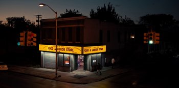 Movie still from “Charm City Kings” (2020), directed by Angel Manuel Soto – People walking on the sidewalk in front of a liquor store at night; Extreme Wide shot, High angle