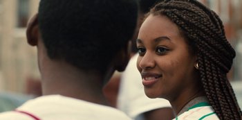 Movie still from “Charm City Kings” (2020), directed by Angel Manuel Soto – A young woman smiles at the camera as she talks to a man; Close Up shot, Over the shoulder angle