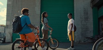 Movie still from “Charm City Kings” (2020), directed by Angel Manuel Soto – A group of young people standing next to each other near a green door; Wide shot, Over the shoulder angle
