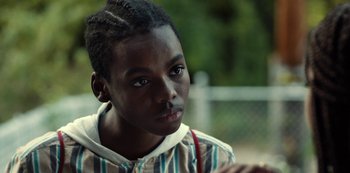 Movie still from “Charm City Kings” (2020), directed by Angel Manuel Soto – A young boy with a striped shirt is looking at the camera; Close Up shot, Over the shoulder angle