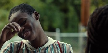 Movie still from “Charm City Kings” (2020), directed by Angel Manuel Soto – A person smiling with trees in the background; Close Up shot, Over the shoulder angle