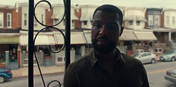 Movie still from “Charm City Kings” (2020), directed by Angel Manuel Soto – A man with a beard is looking out of a window; Close Up shot, Over the shoulder angle