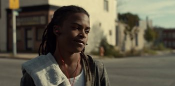 Movie still from “Charm City Kings” (2020), directed by Angel Manuel Soto – A man with dreadlocks wearing a white shirt and a jacket; Close Up shot, Low angle