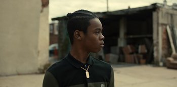 Movie still from “Charm City Kings” (2020), directed by Angel Manuel Soto – A young man wearing a necklace with a tag on it; Close Up shot, Over the shoulder angle