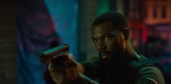 Movie still from “Charm City Kings” (2020), directed by Angel Manuel Soto – A man holding a gun while wearing a black shirt; Close Up shot, Over the shoulder angle