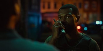 Movie still from “Charm City Kings” (2020), directed by Angel Manuel Soto – A man sitting in front of a window while talking on a cell phone; Close Up shot, Over the shoulder angle
