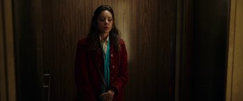 Movie still from “Child's Play” (2019), directed by Lars Klevberg – A woman in a red coat standing in front of a wooden wall; Medium shot, Low angle