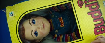 Movie still from “Child's Play” (2019), directed by Lars Klevberg – A child's doll in a box with blue eyes; Close Up shot, Overhead angle